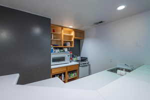 Kitchen featuring recessed lighting, white appliances, open shelves, visible vents, and a sink
