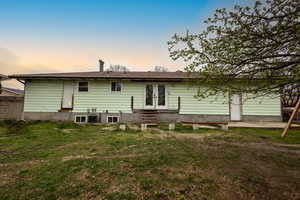 Back of property with entry steps, french doors, and a lawn