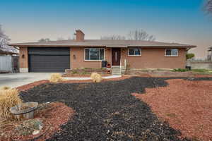 Ranch-style house featuring brick siding, driveway, a garage, and a chimney