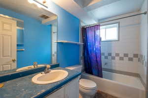 Full bathroom featuring visible vents, toilet, shower / tub combo with curtain, and vanity