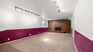 Unfurnished living room featuring carpet flooring, baseboards, a fireplace, and a textured ceiling