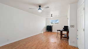Home office with a ceiling fan, baseboards, and light wood-type flooring