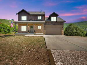 View of front of house featuring concrete driveway, a garage, and a porch