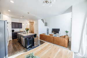 Kitchen with a kitchen breakfast bar, dark wood-style flooring, stainless steel appliances, a sink, and dark brown cabinets