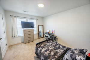 Bedroom featuring light carpet, baseboards, and visible vents