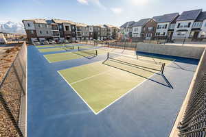 View of tennis court with community basketball court, fence, and a residential view