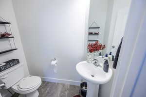 Half bathroom featuring baseboards, toilet, and a sink