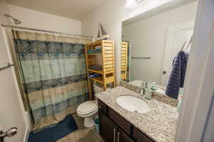 Bathroom featuring toilet, vanity, and a shower with curtain