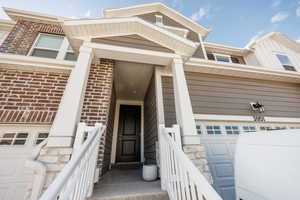 View of exterior entry with stone siding, brick siding, and a garage