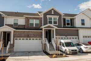 Multi unit property featuring concrete driveway, an attached garage, brick siding, board and batten siding, and a shingled roof