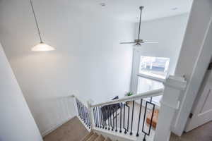 Stairway featuring carpet flooring, a high ceiling, and ceiling fan