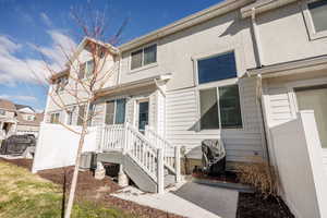 Back of house with fence, stucco siding, and central air condition unit