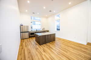 Kitchen featuring light countertops, stainless steel appliances, recessed lighting, light wood-type flooring, and a center island