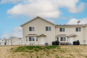 Rear view of property featuring central air condition unit, a patio, and a yard
