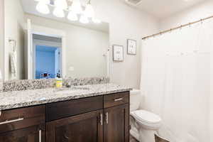 Full bathroom with visible vents, toilet, and vanity
