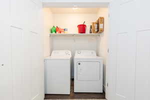 Laundry room featuring dark wood finished floors, washing machine and dryer, and laundry area