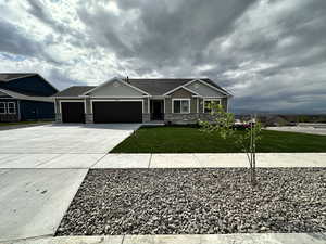 Craftsman inspired home with an attached garage, stone siding, a front yard, and concrete driveway