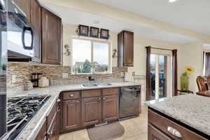 Kitchen with a sink, a wealth of natural light, black appliances, and backsplash