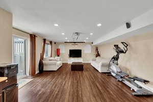 Living area featuring baseboards, dark wood-style floors, an accent wall, and recessed lighting
