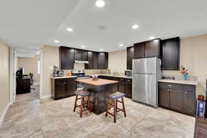 Kitchen with baseboards, recessed lighting, stainless steel appliances, and dark brown cabinets