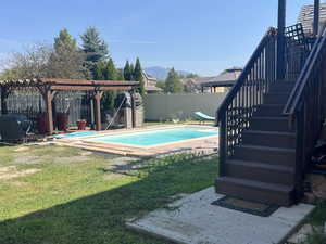 View of swimming pool featuring a fenced backyard, a fenced in pool, a mountain view, and a yard