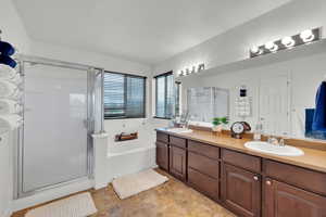 Bathroom with double vanity, a sink, a stall shower, and a garden tub