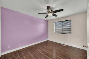 Empty room with baseboards, visible vents, wood finished floors, and ceiling fan