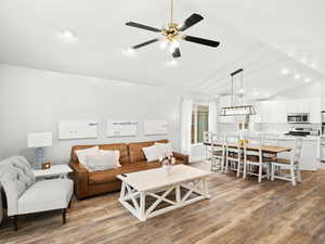 Living room featuring lofted ceiling, ceiling fan, recessed lighting, and light wood-style floors
