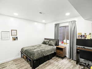 Bedroom with baseboards, visible vents, wood finished floors, and recessed lighting