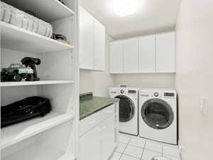 Laundry room with washer and clothes dryer, cabinet space, and light tile patterned floors
