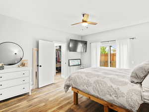Bedroom with a spacious closet, a ceiling fan, a closet, and light wood-style floors