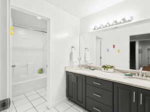 Bathroom with double vanity, a sink, tile patterned flooring, and shower / bathtub combination