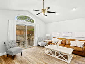 Living area featuring a ceiling fan, light wood-style flooring, baseboards, and lofted ceiling