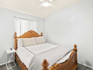 Bedroom featuring baseboards, carpet flooring, lofted ceiling, and ceiling fan