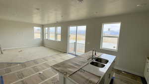 Kitchen featuring a sink, a water view, baseboards, and a textured ceiling