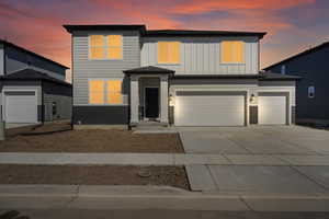 View of front of house with an attached garage, board and batten siding, and concrete driveway