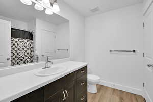 Bathroom featuring vanity, toilet, baseboards, visible vents, and wood finished floors