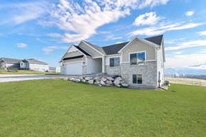 Craftsman-style home with board and batten siding, a front yard, stone siding, and a garage