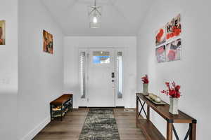 Foyer entrance with lofted ceiling, visible vents, and wood finished floors