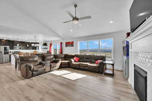 Living room featuring a fireplace, light wood-style floors, ceiling fan, and recessed lighting