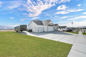 View of property exterior with a lawn, concrete driveway, roof with shingles, and an attached garage