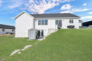 Rear view of house featuring a shingled roof and a lawn