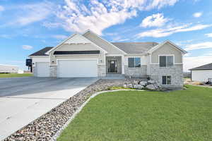 Craftsman inspired home with driveway, stone siding, an attached garage, board and batten siding, and a front lawn