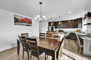 Dining room with visible vents, baseboards, recessed lighting, light wood-type flooring, and a notable chandelier