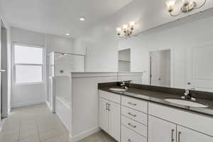 Bathroom with tile patterned flooring, a sink, double vanity, and an enclosed shower