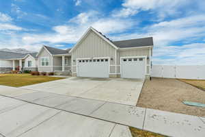 View of front of house featuring board and batten siding, a gate, concrete driveway, and an attached garage