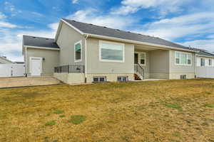 Back of house featuring a gate, stucco siding, fence, and a lawn