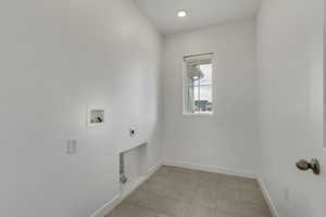 Laundry room featuring hookup for an electric dryer, light tile patterned floors, hookup for a washing machine, baseboards, and laundry area