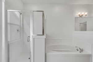 Full bath with a stall shower, a notable chandelier, and a garden tub