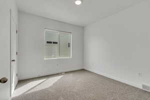 Carpeted spare room featuring baseboards and visible vents